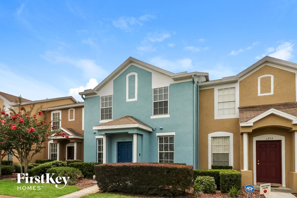 A row of houses with the first one being blue and the second one being tan.