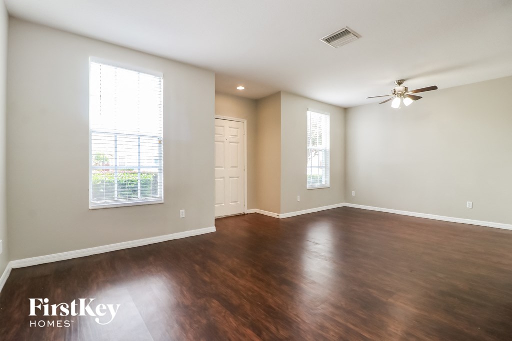 A spacious room with wooden floors and a ceiling fan.