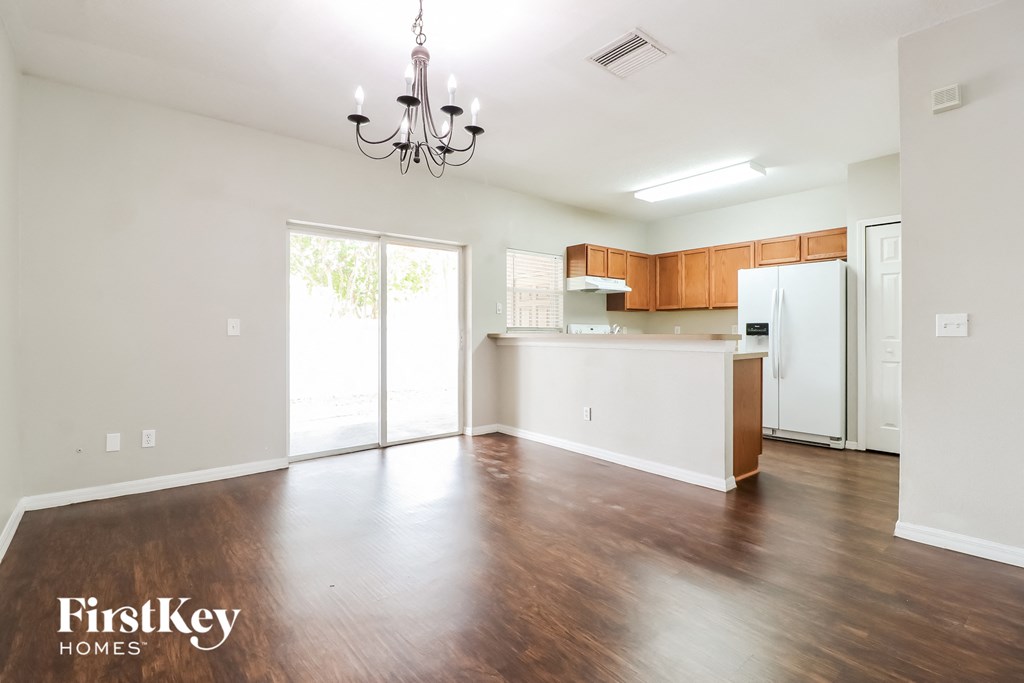 A spacious living room with wooden floors and a chandelier.