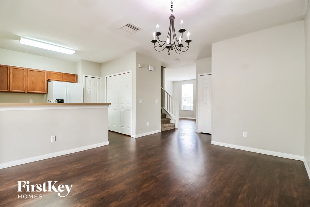 A spacious living room with wooden floors and a chandelier.