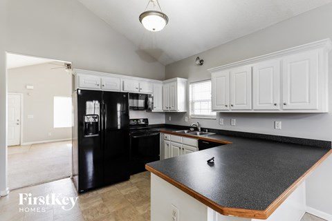A kitchen with black appliances and white cabinets.