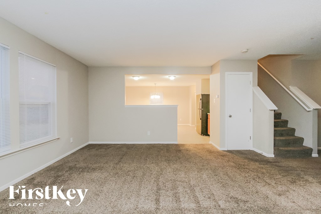 A spacious room with a staircase leading to another room.