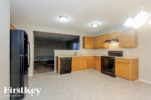 A kitchen with wooden cabinets and a black fridge.