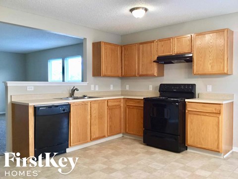 A kitchen with wooden cabinets and black appliances.