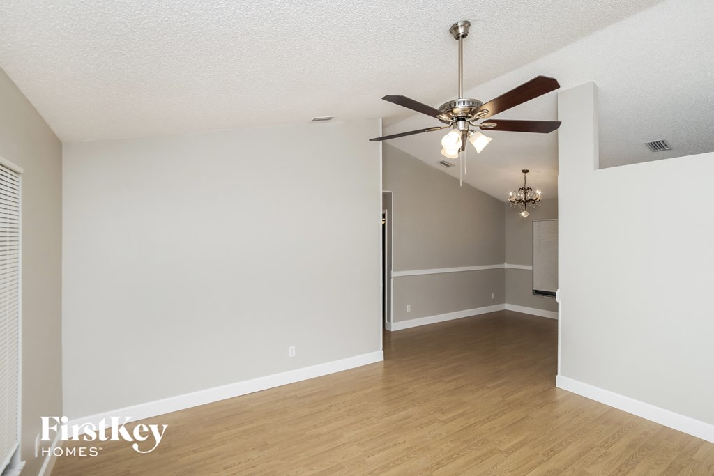 an empty living room with a ceiling fan and white walls