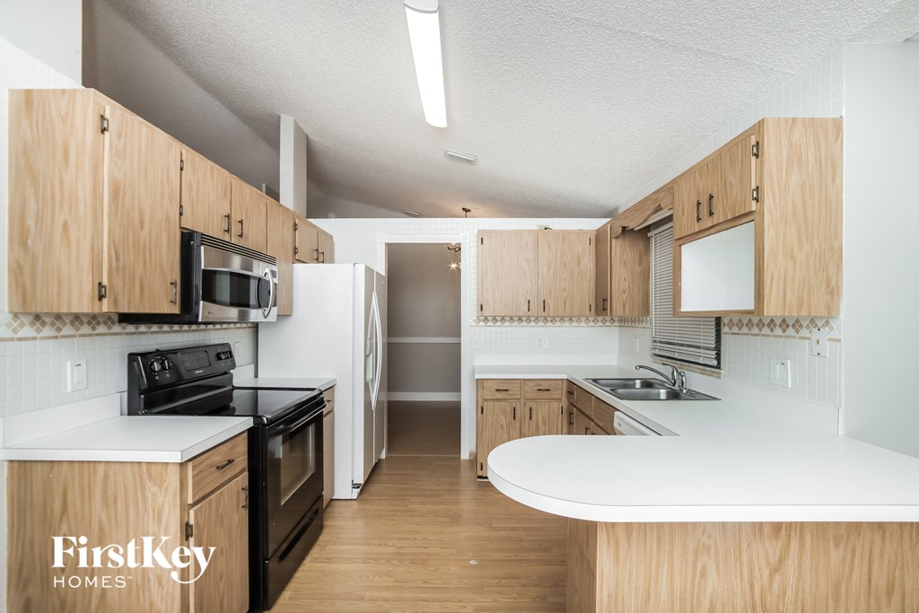 a kitchen with white counters and wooden cabinets and a black stove and refrigerator