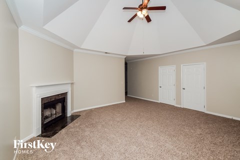 A spacious room with a fireplace and a ceiling fan.