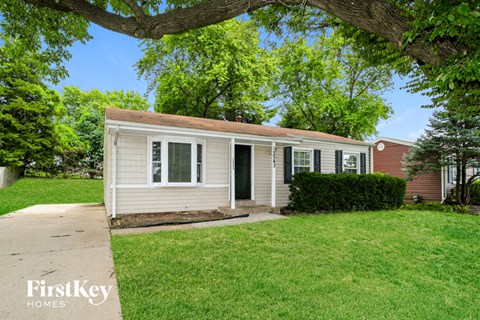 A small house with a porch is surrounded by a green lawn.