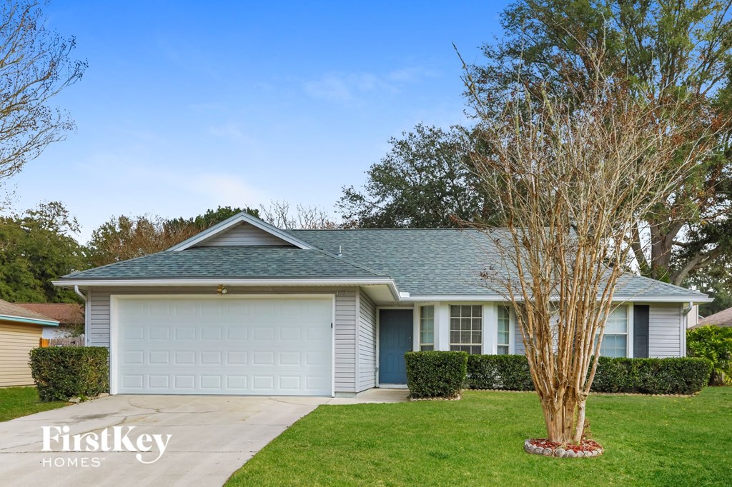 a white house with a blue roof and a tree