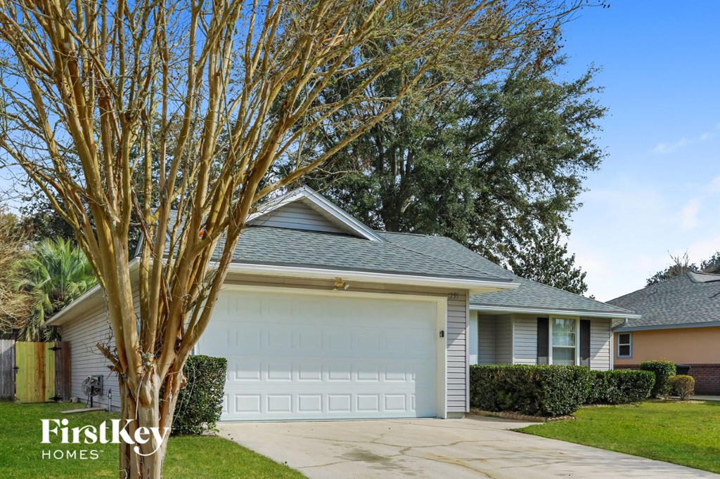 a home with a white garage door and a tree