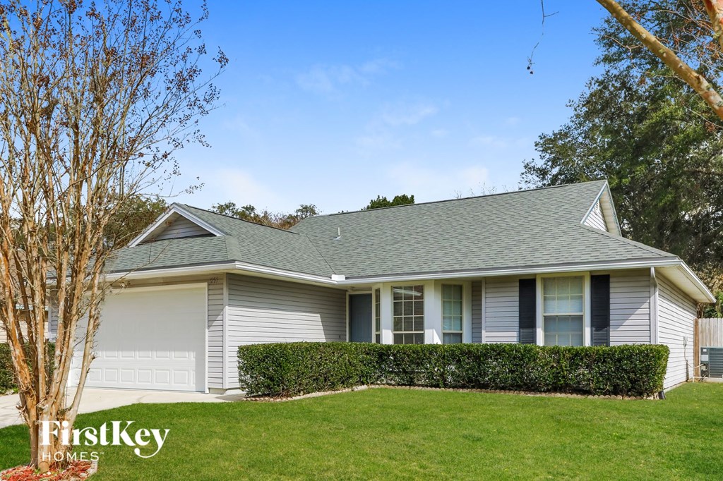 a white house with a lawn and hedges