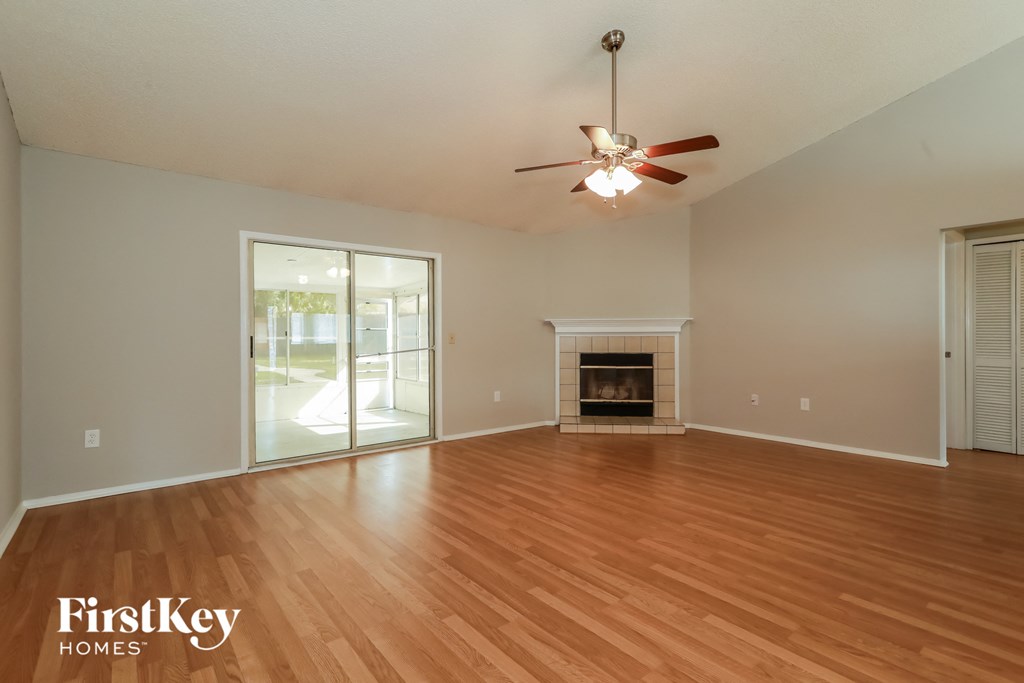 an empty living room with a fireplace and a ceiling fan
