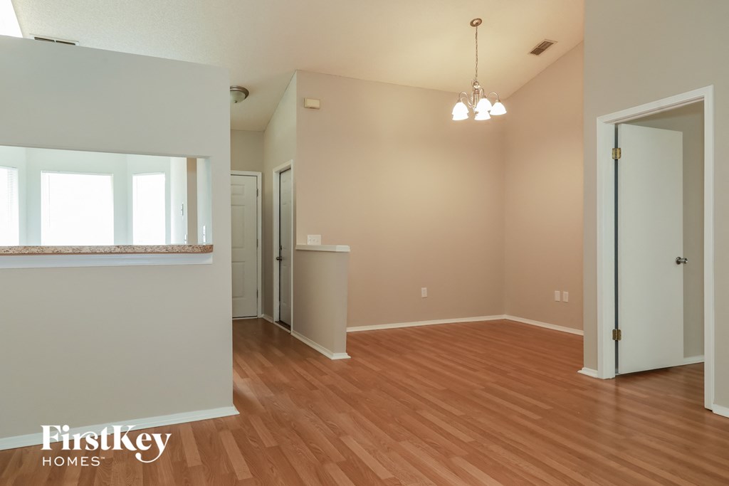 the living room and dining room of an empty house with wood flooring