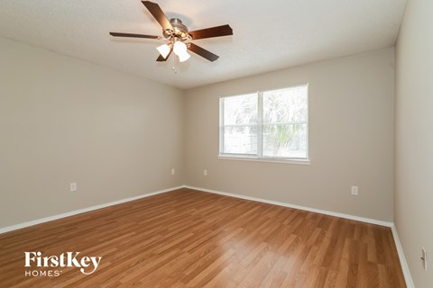 the spacious living room with hardwood flooring and a ceiling fan