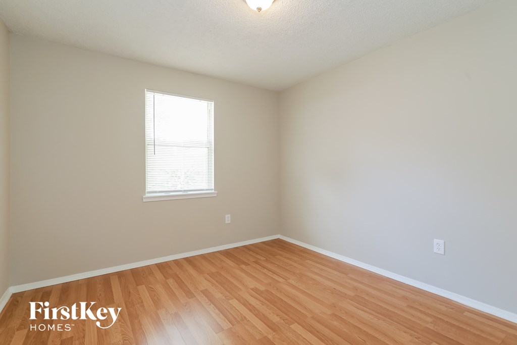 a bedroom with wood flooring and a window