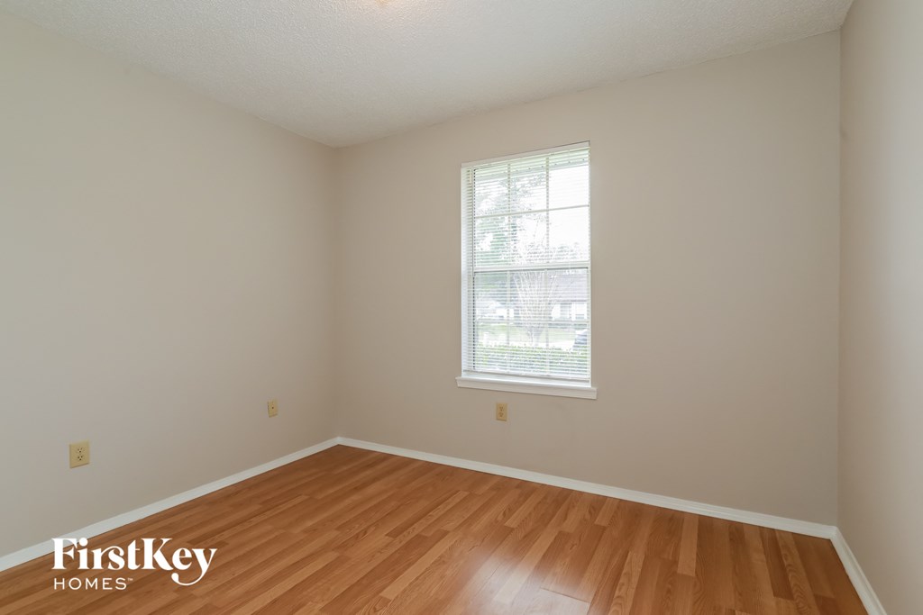 a bedroom with a hard wood floor and a window