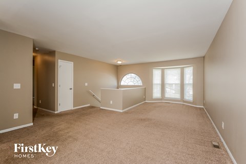 A spacious room with a carpeted floor and a large window.