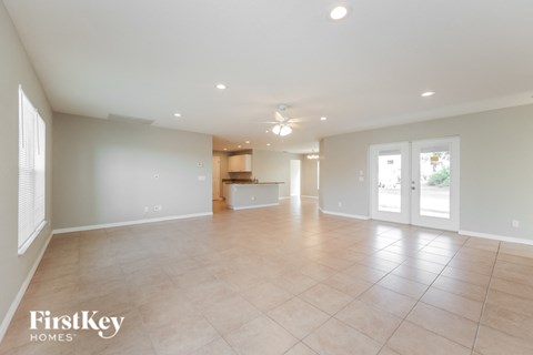 an empty living room with a kitchen in the background