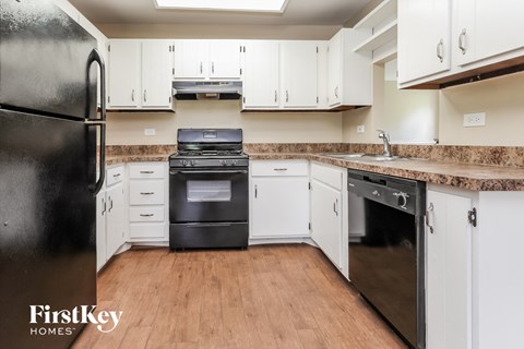 a kitchen with white cabinets and black appliances and a wood floor