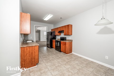 a kitchen with wood cabinets and black appliances and a tile floor