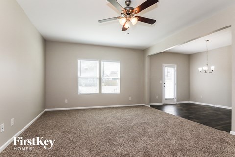 A spacious room with a ceiling fan and carpeted floor.