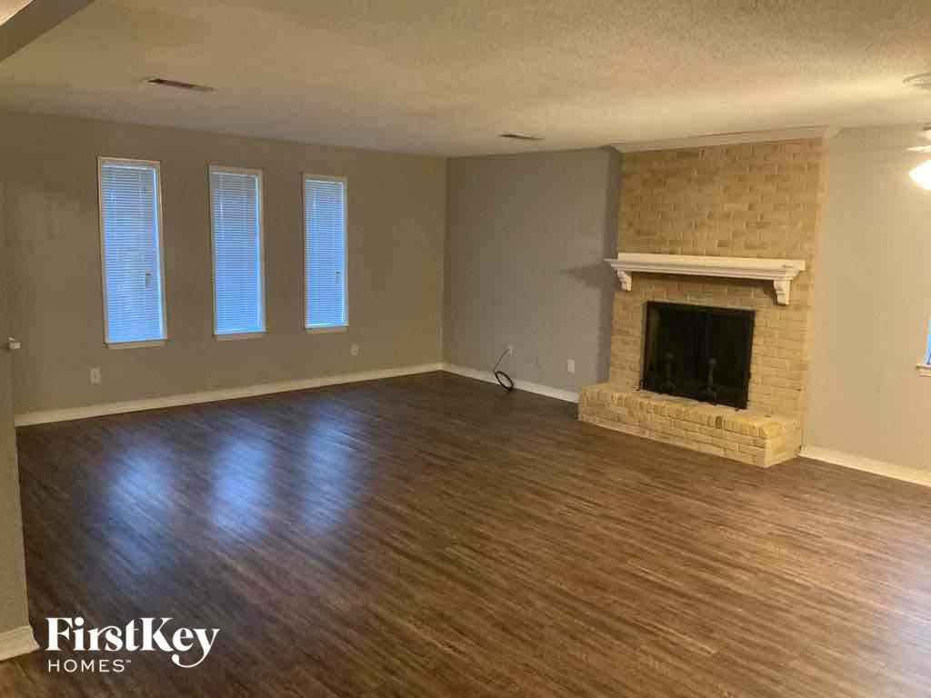 an empty living room with a fireplace and wooden floors
