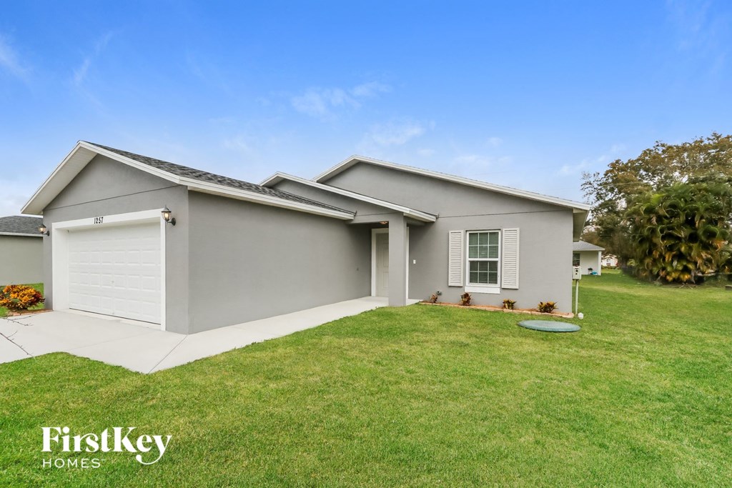 the exterior of a gray house with a lawn and a driveway
