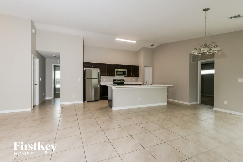 a large kitchen with a large tiled floor and a stainless steel refrigerator