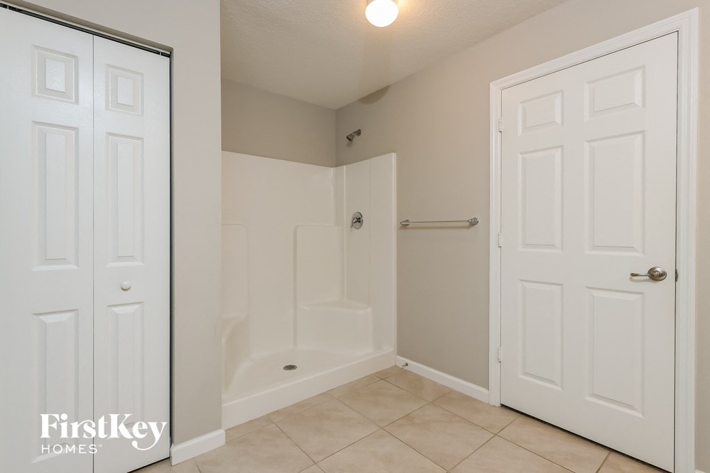 a bathroom with a shower and a toilet and a white door