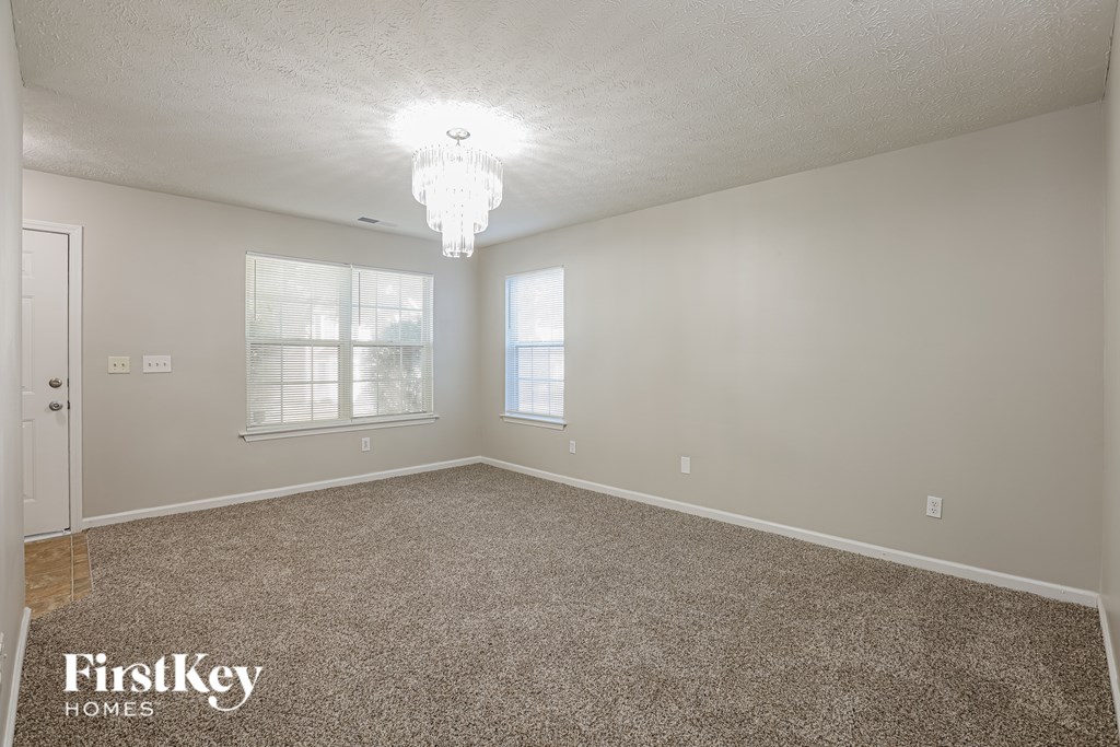A spacious room with a carpeted floor and a chandelier hanging from the ceiling.