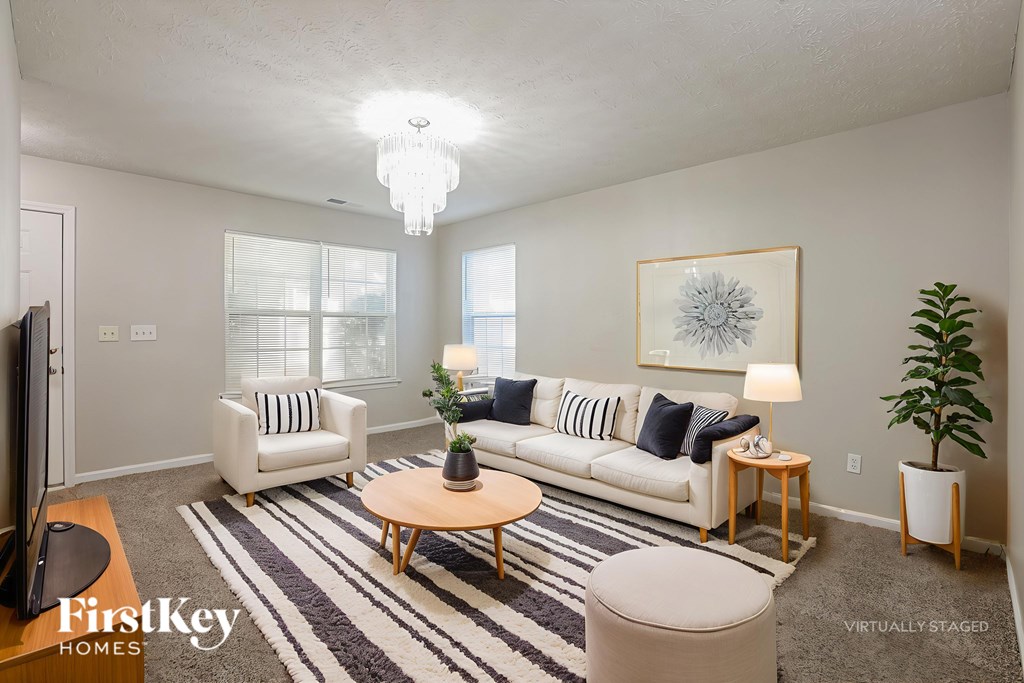 A living room with a white couch, a coffee table, and a rug.