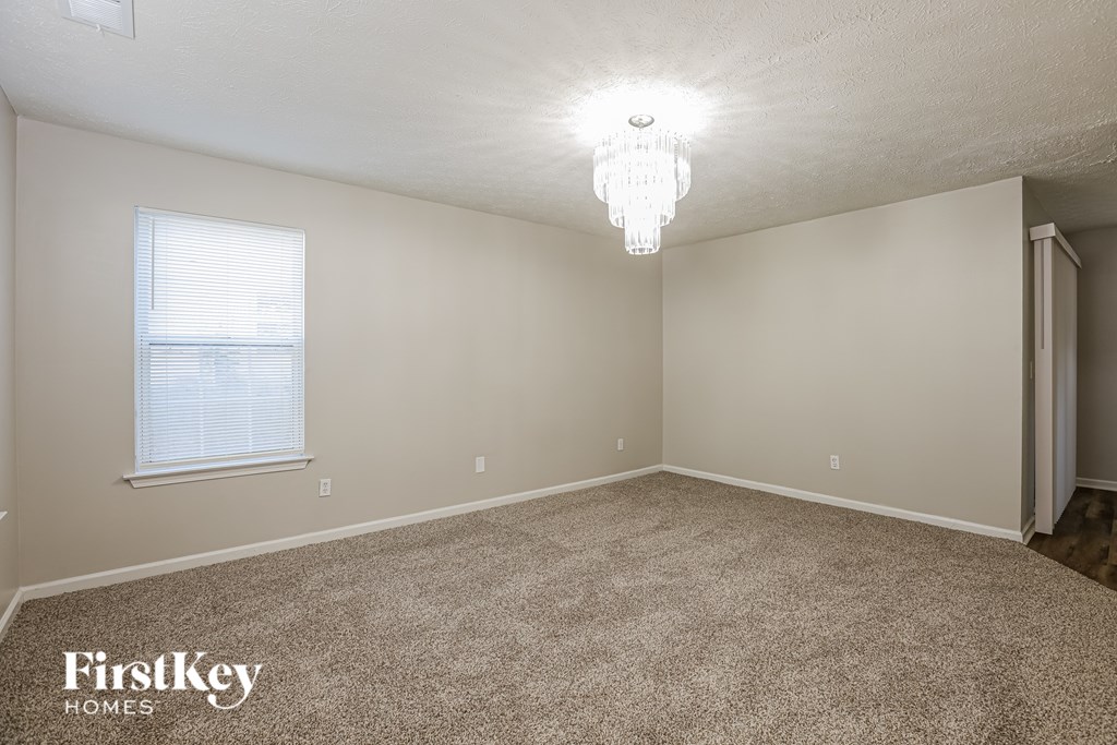 A room with a carpeted floor and a chandelier hanging from the ceiling.