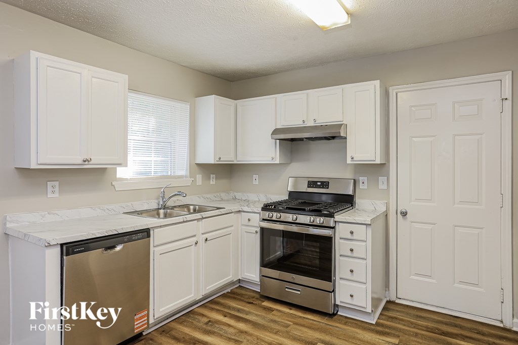 A kitchen with white cabinets and a stainless steel refrigerator.