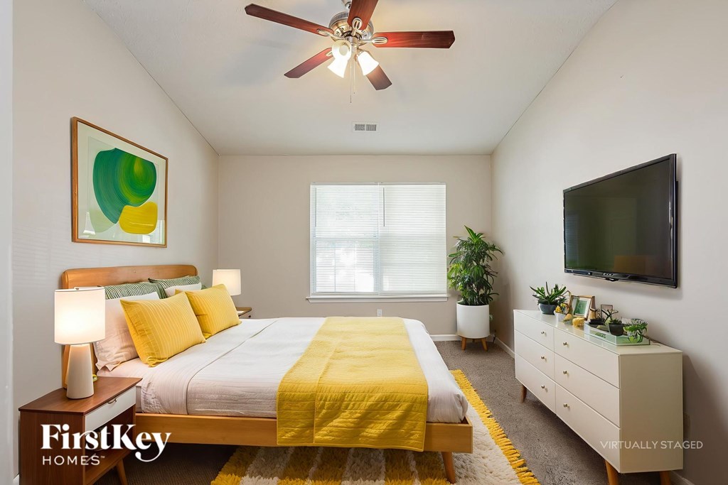 A bedroom with a bed, dresser, and television.