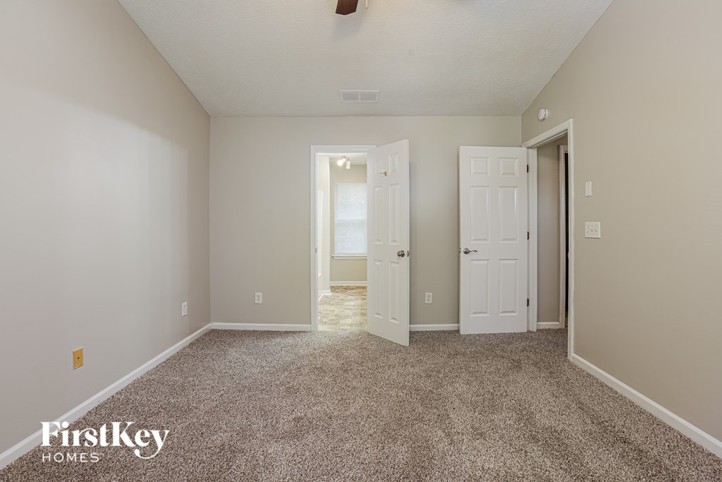 A room with a carpeted floor and two white doors.