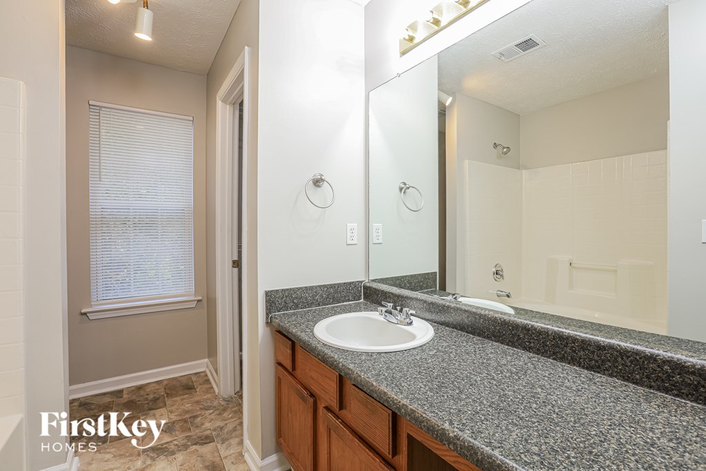 A bathroom with a granite countertop and a large mirror.
