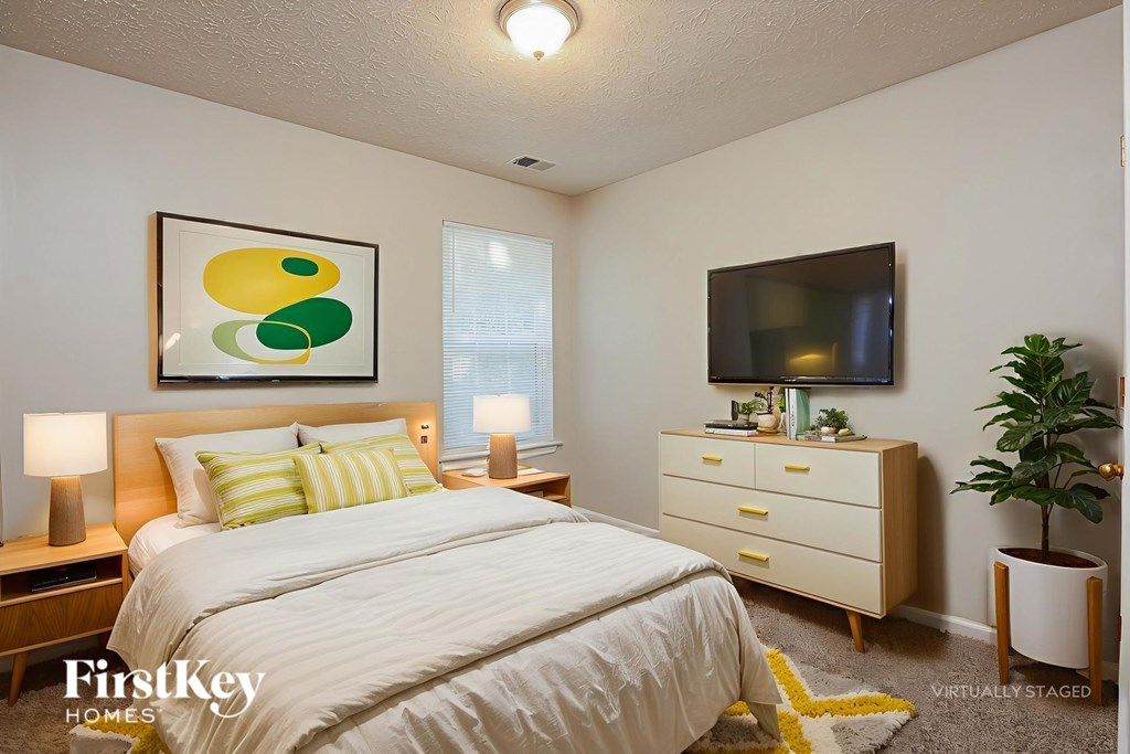 A bedroom with a bed, nightstand, and a painting on the wall.