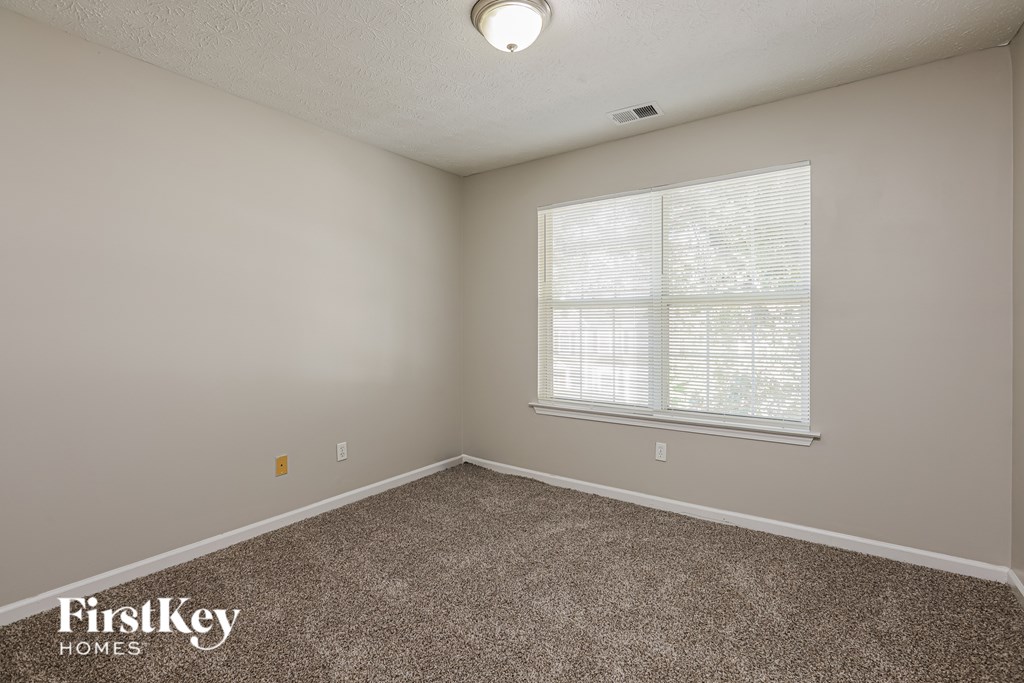 A room with a carpeted floor and a window with blinds.