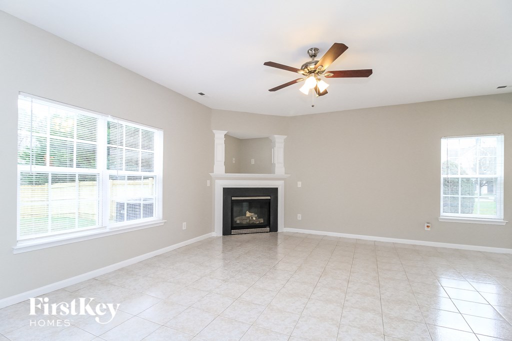 an empty living room with a fireplace and a ceiling fan