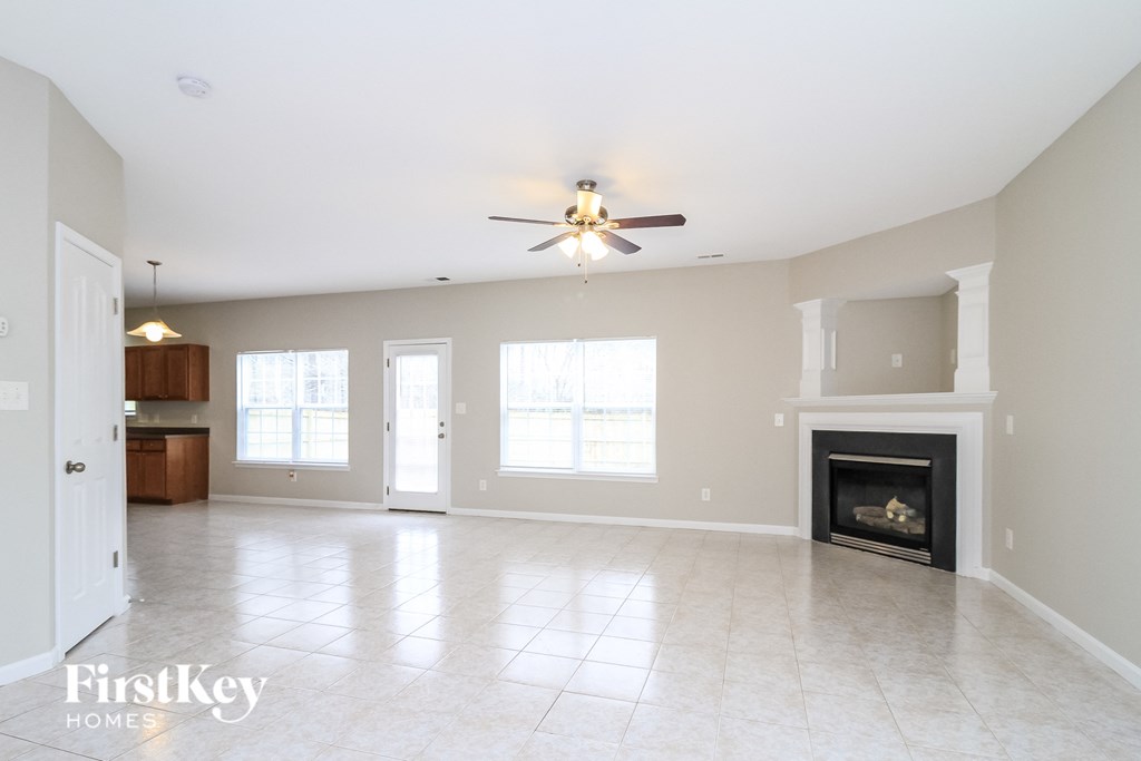 an empty living room with a fireplace and a ceiling fan