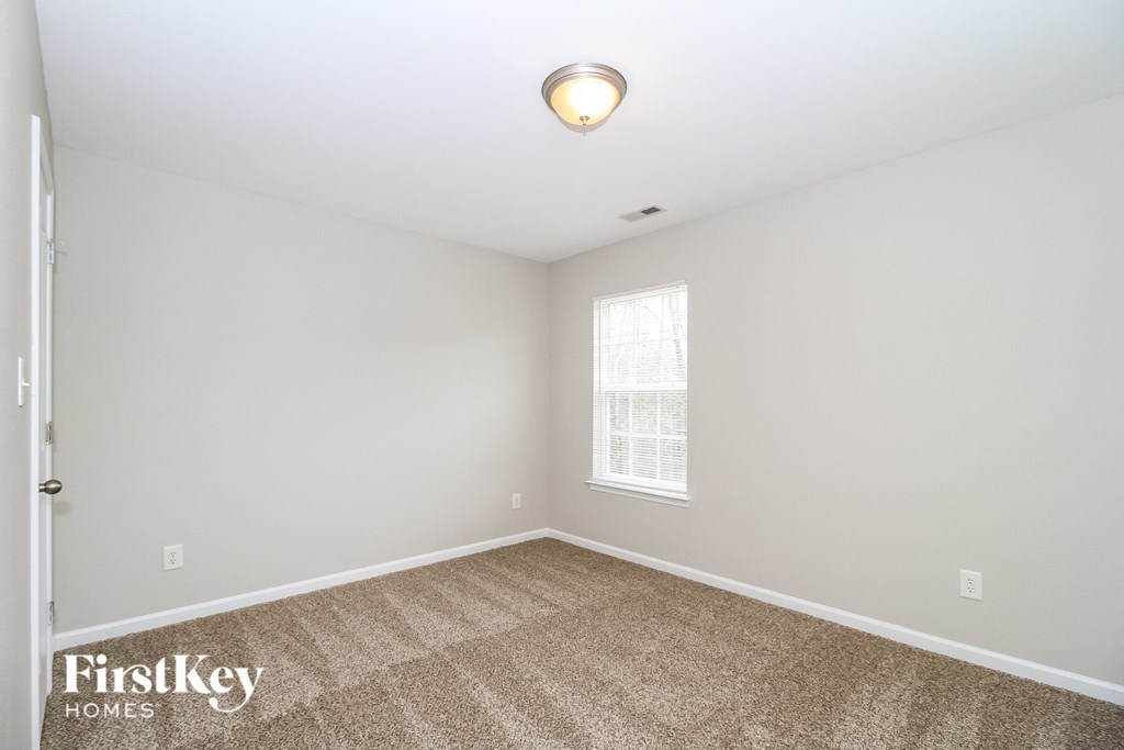 the spacious living room with carpeting and a window