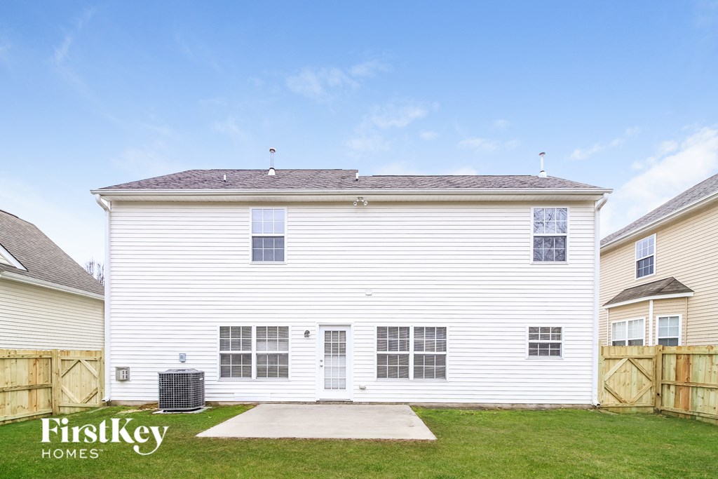 side view of a white house with a driveway and grass