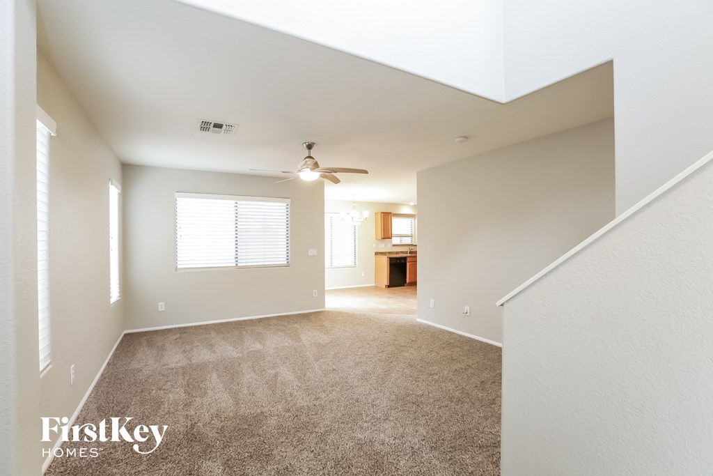 a spacious living room with carpet and a ceiling fan