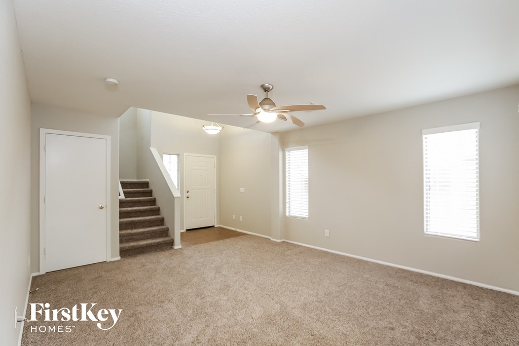 a spacious living room with carpet and a ceiling fan