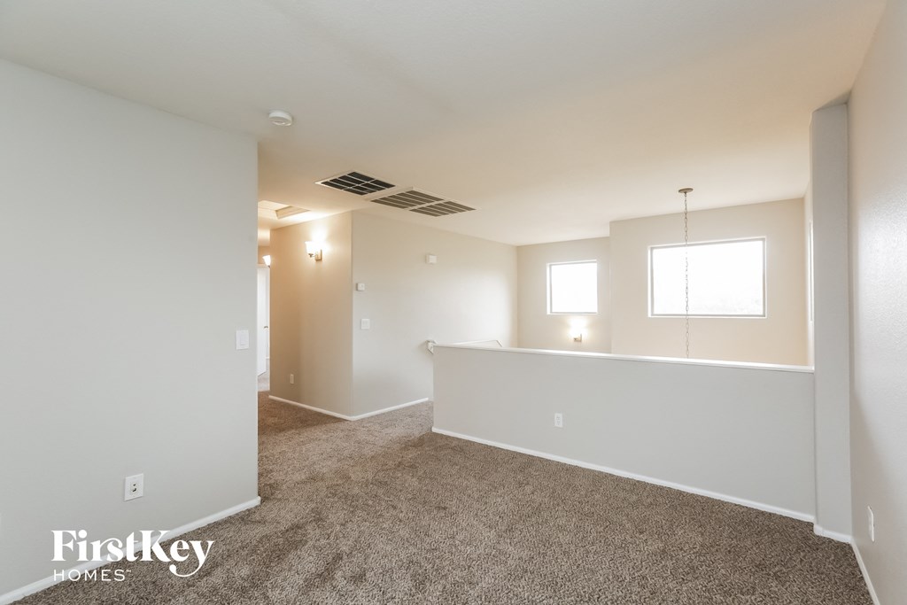 a living room with carpet and a kitchen with white walls