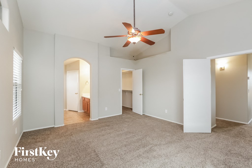 a spacious living room with carpet and a ceiling fan