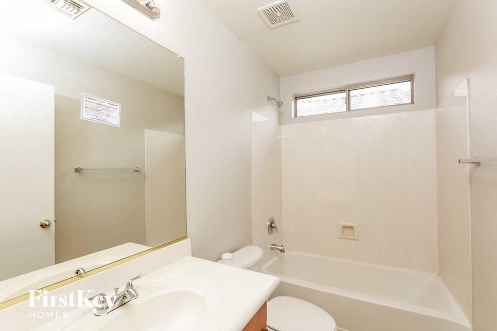 a white bathroom with a tub and a sink and a mirror