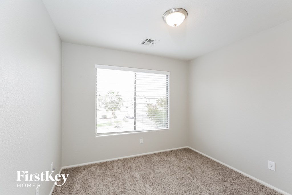 a bedroom with a large window and carpeted floor