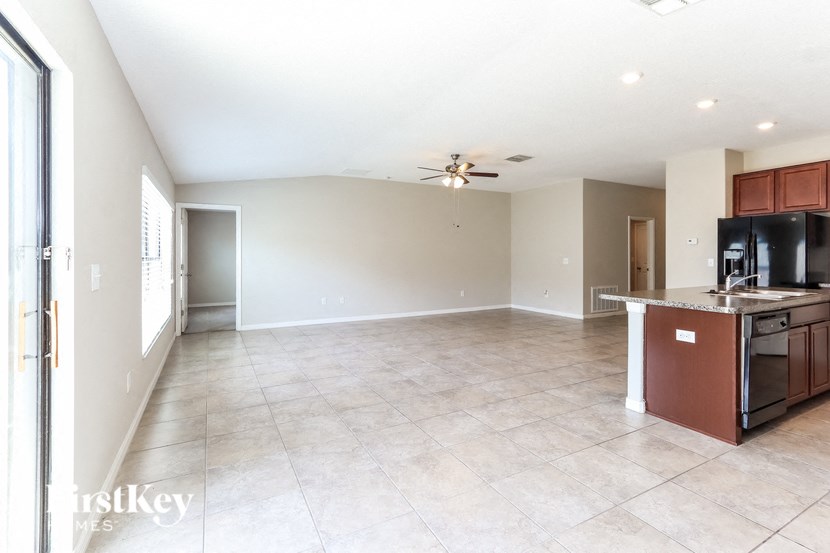 A spacious kitchen and living room with a tile floor and a ceiling fan.