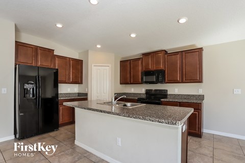 A kitchen with a black refrigerator and brown cabinets.